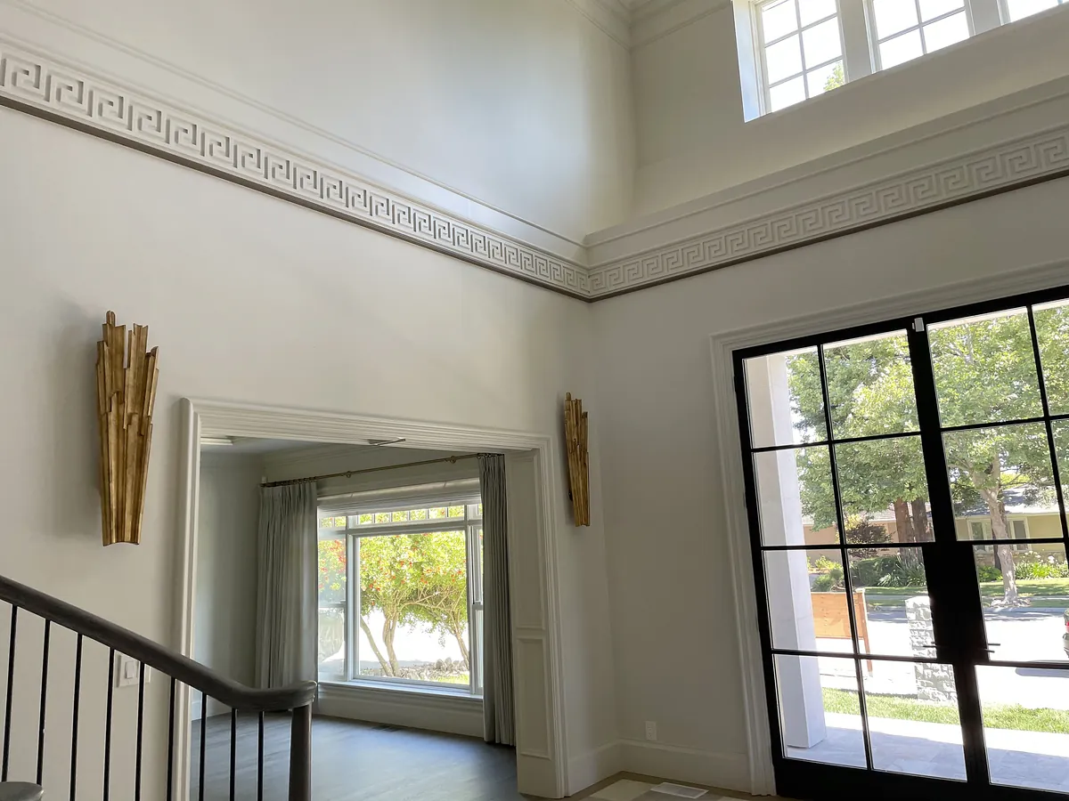 Double-height entry with Greek-key molding and steel-framed doors