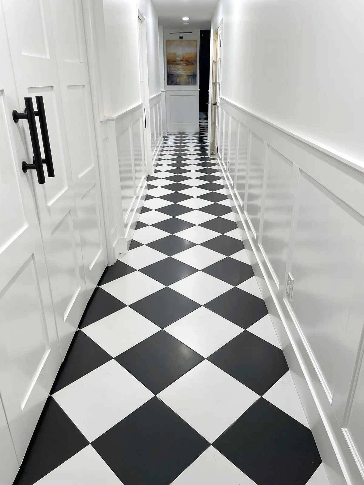 Long hallway with black-and-white checkerboard tile and wainscoting