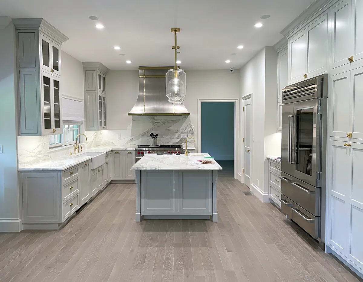Wide view of the gray shaker kitchen with island and built-in refrigerator