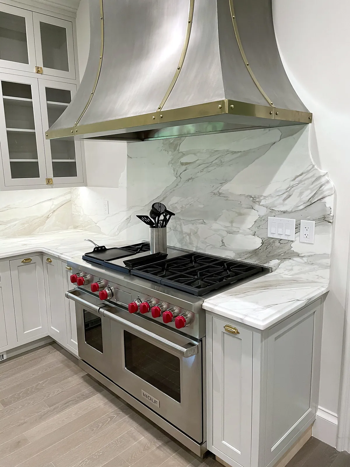 Professional range with red knobs set in a marble backsplash