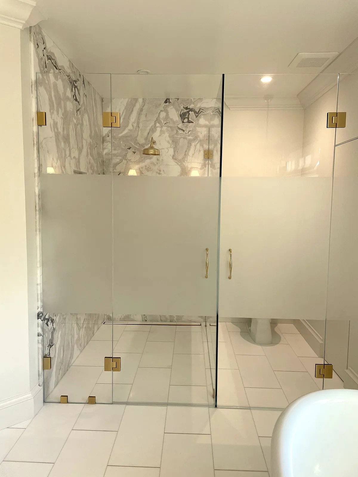 Glass shower with marble walls and brass fixtures