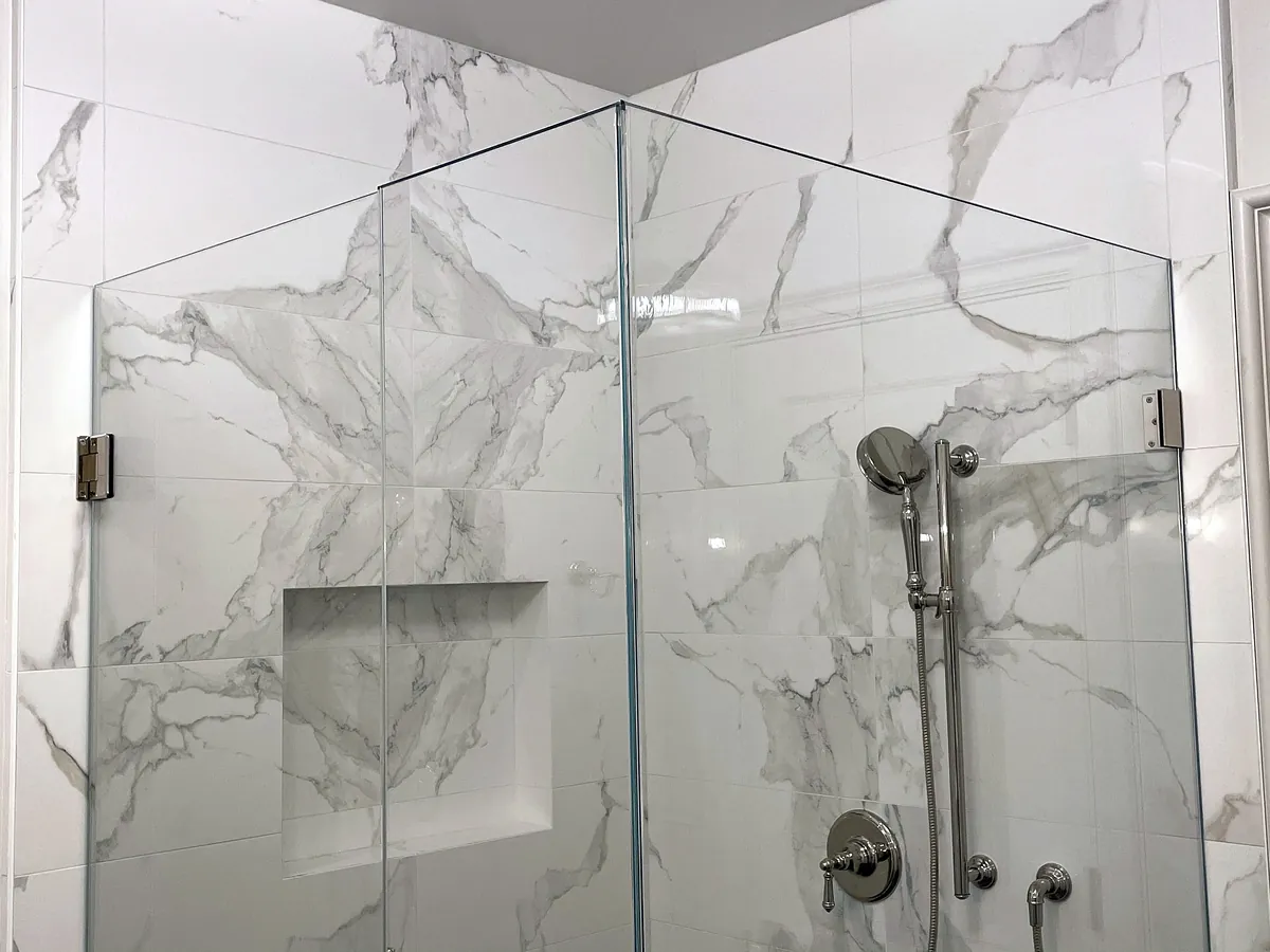 Marble slab shower with glass enclosure and niche