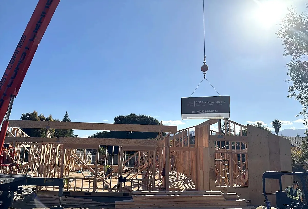 Crane lifting the PFB Construction sign over a new home's framing
