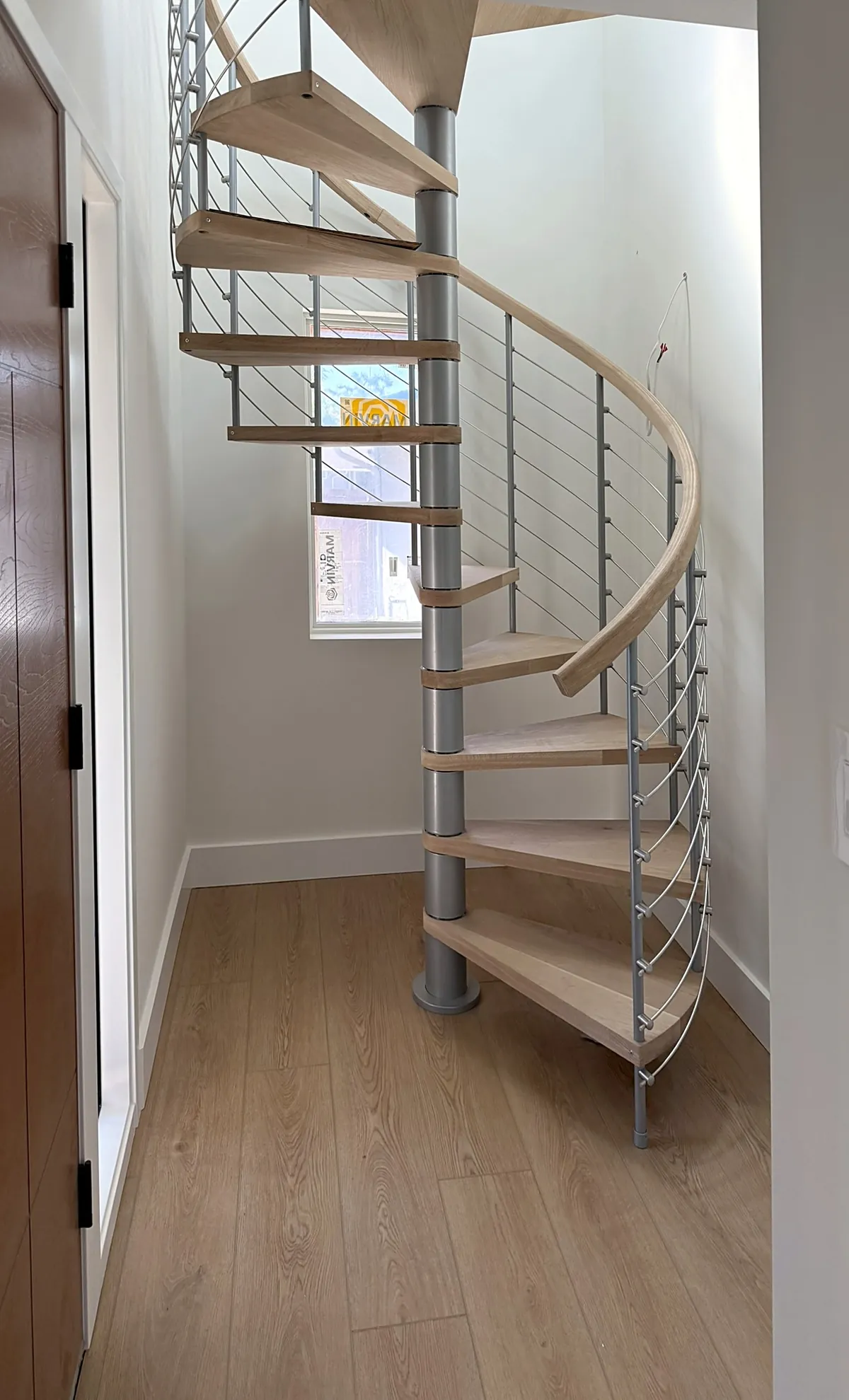 Spiral stair with light-oak treads, a curved handrail and cable balusters